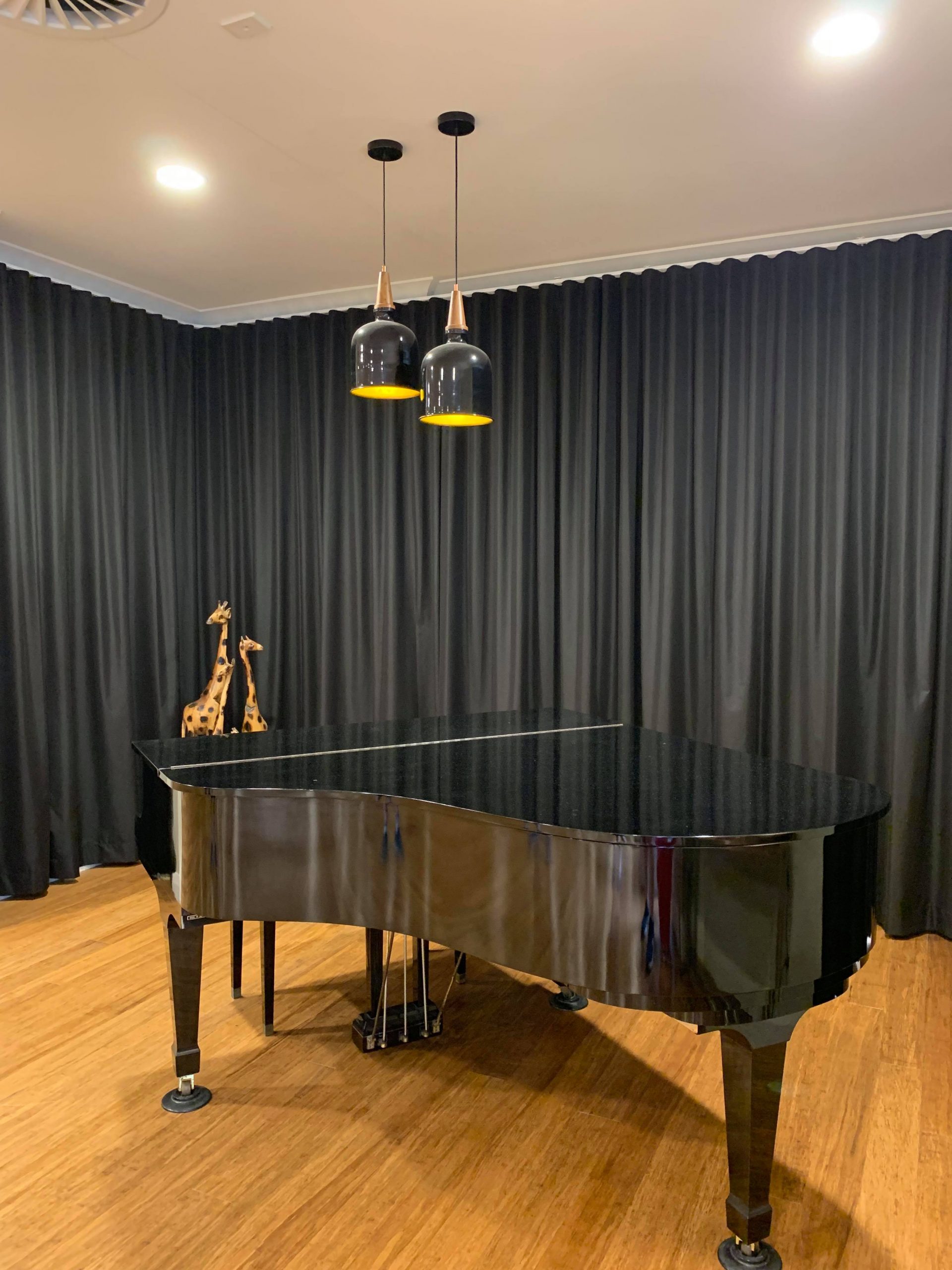 A black baby grand piano in a game room with heavy dark curtains | Game Room Curtains Blog Featured Image