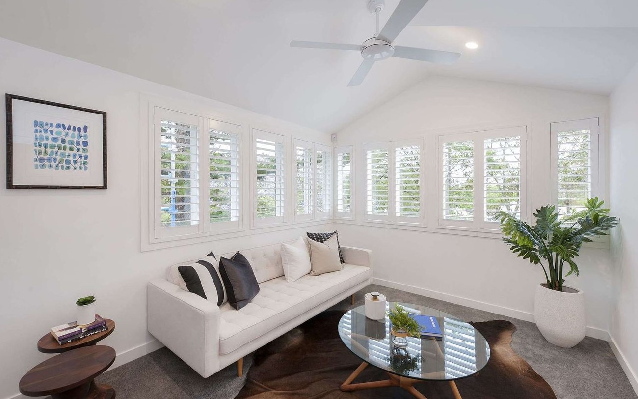 A modern living room with couch and shutters in the windows.