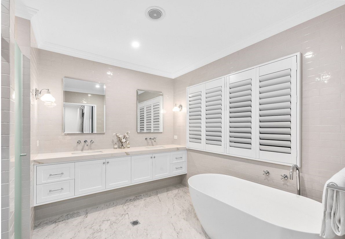 A bathroom with a freestanding bath and white shutters | Featured image for the blog How to Clean Shutters.